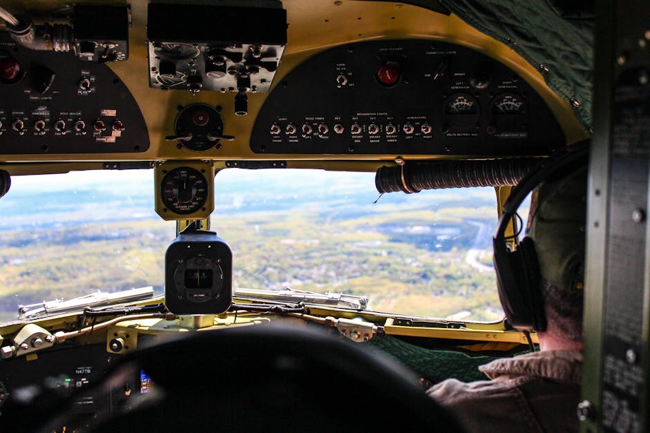 Pilot's perspective inside a cockpit flying over a scenic landscape on a clear day.